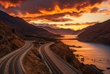 Tranquil sunset over picturesque lake with winding road, scenic nature landscape