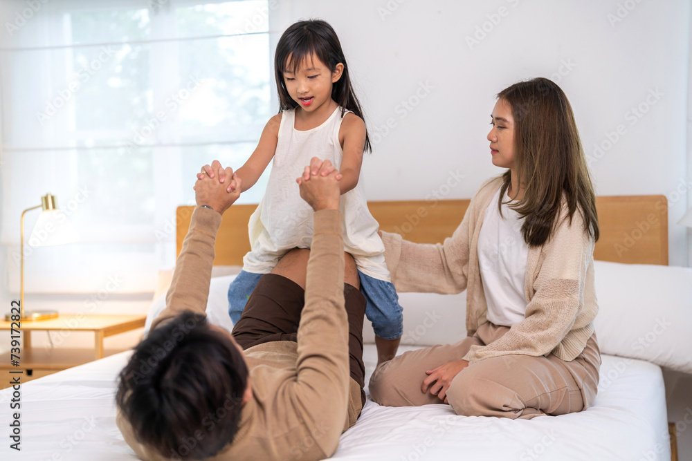 Fototapeta premium Portrait of enjoy happy love asian family father and mother holding hug cute little asian girl child smiling play and having fun moments good time, care, kid, support, insurance, child, at home