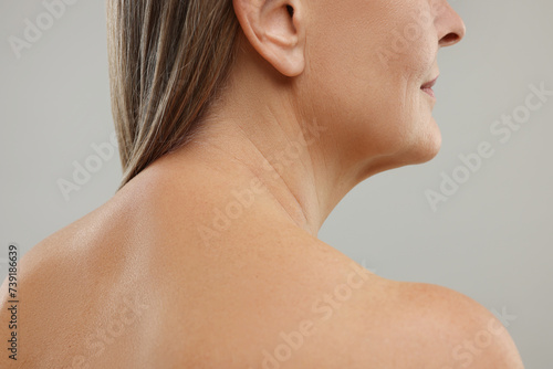 Mature woman with healthy skin on grey background, closeup