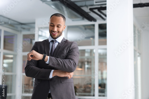 Happy man looking at his watch in office, space for text. Lawyer, businessman, accountant or manager