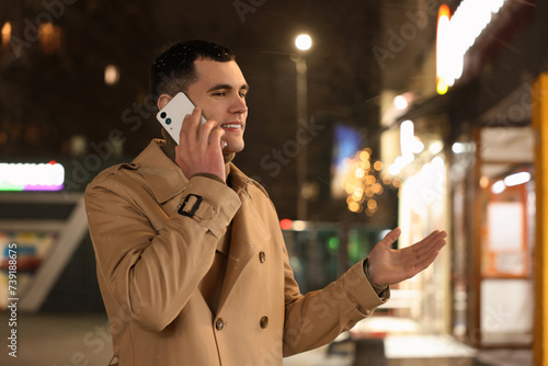 Man talking by smartphone on night city street