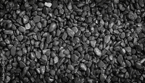 Close-up of textured black rocks or gravel, uniformly spread. Highlights natural patterns and shapes
