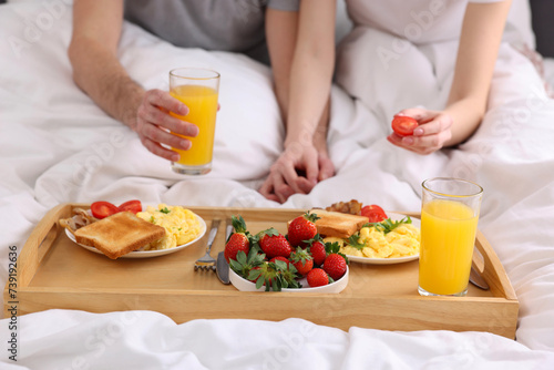 Couple eating tasty breakfast in bed, closeup