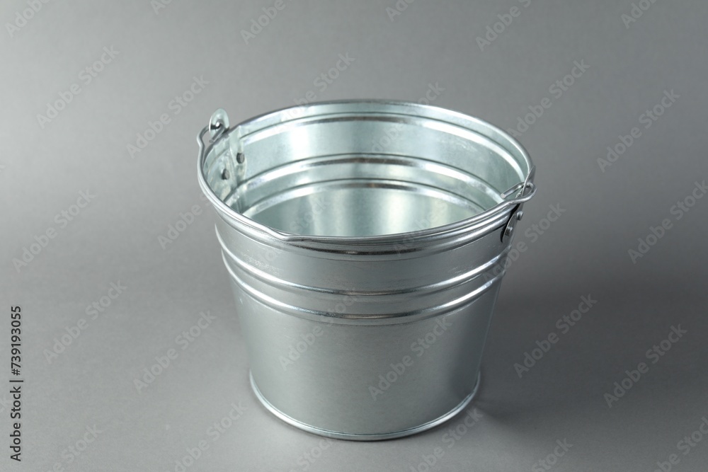 One shiny metal bucket on light grey background One shiny metal bucket on light grey background