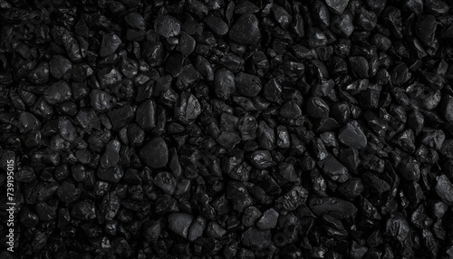 Close-up of textured black rocks or gravel, uniformly spread. Highlights natural patterns and shapes