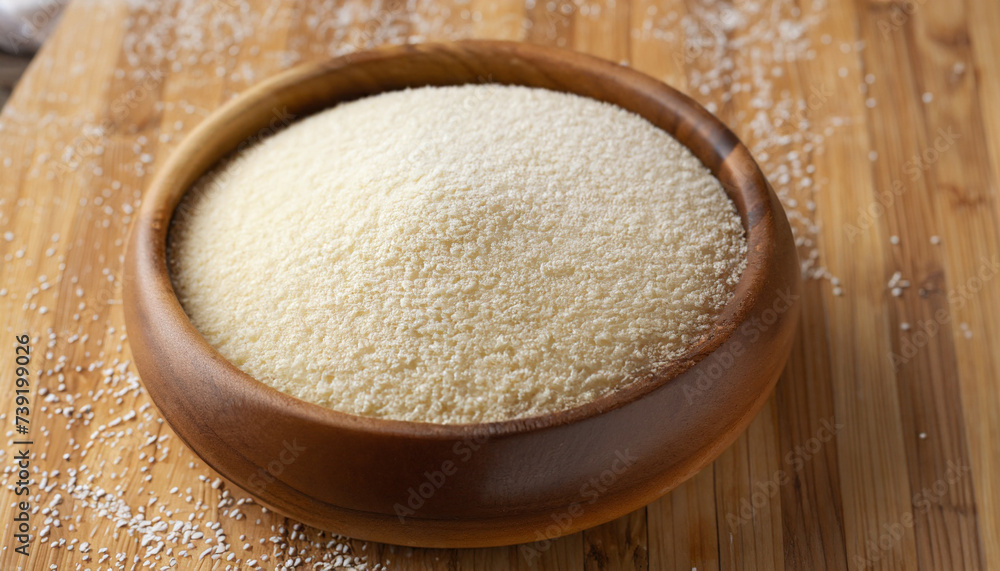 Semolina in wooden bowl on brown bamboo board, closeup. Rustic style, healthy dietary groats background. Semolina in wooden bowl on brown bamboo board, closeup. Rustic style, healthy dietary groats background.