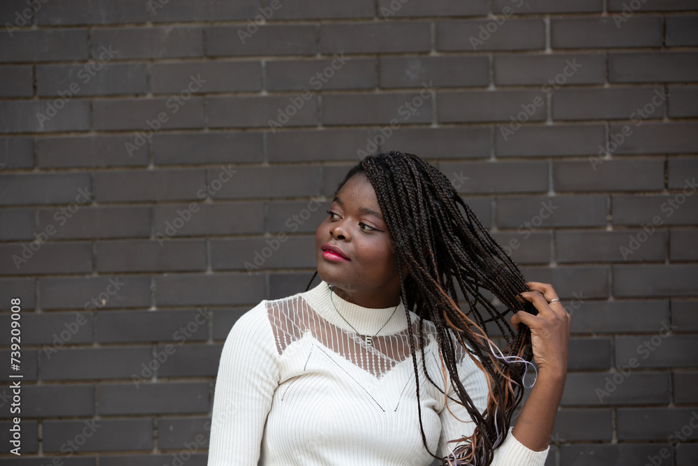 Portrait of beautiful young African American woman showing long black hair braided hairstyle while feeling happy and smiling in the city outdoor Portrait of beautiful young African American woman showing long black hair braided hairstyle while feeling happy and smiling in the city outdoor