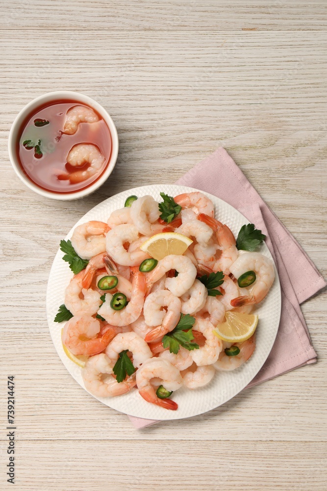 Tasty boiled shrimps with cocktail sauce, chili, parsley and lemon on light wooden table, flat lay