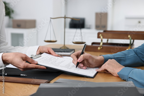 Senior woman signing document in lawyer's office, closeup photo