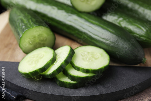 Fresh whole and cut cucumbers on table, closeup