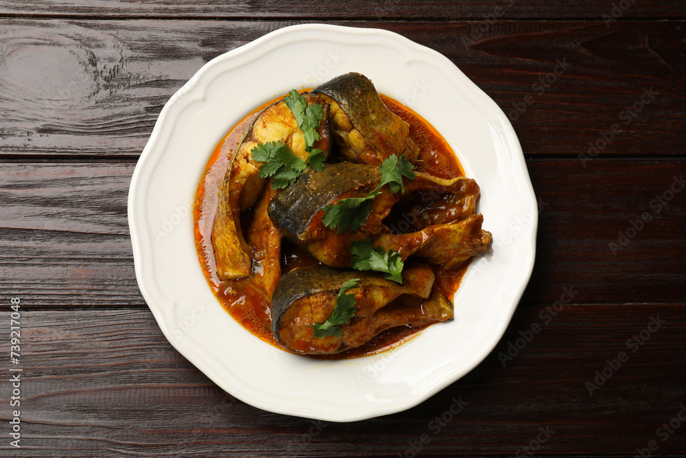 Tasty fish curry on wooden table, top view. Indian cuisine