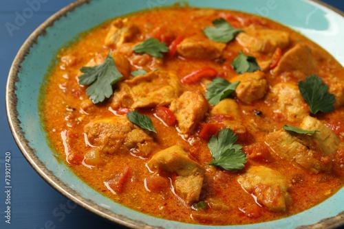 Delicious chicken curry on blue table, closeup