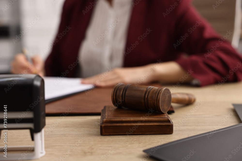 Notary signing document at wooden table in office, focus on gavel
