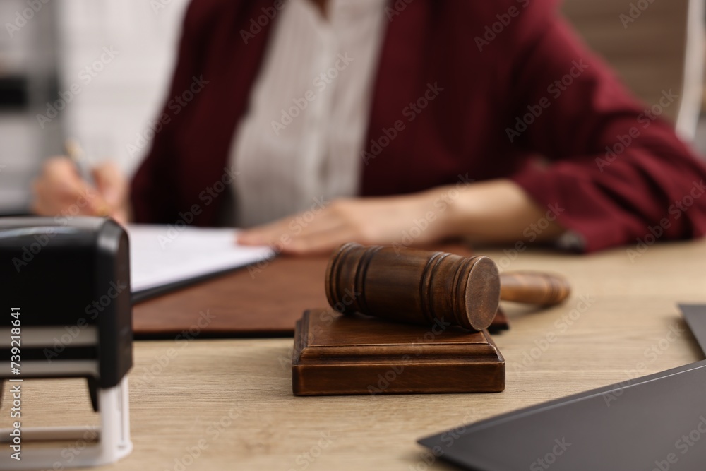 Notary signing document at wooden table in office, focus on gavel Notary signing document at wooden table in office, focus on gavel