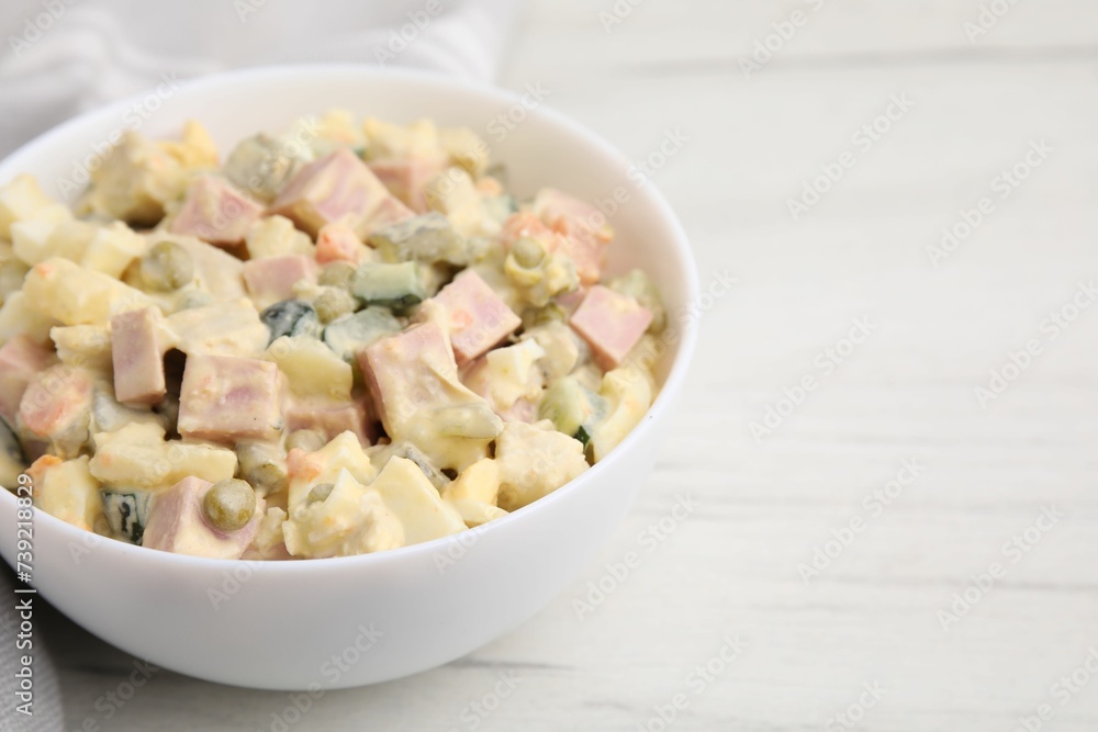 Tasty Olivier salad with boiled sausage in bowl on white table, closeup. Space for text Tasty Olivier salad with boiled sausage in bowl on white table, closeup. Space for text