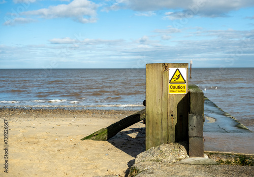 Warning sign on a concrete jetty on Mundesley beach, Norfolk coast photo