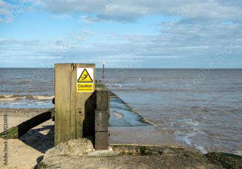 Warning sign on a concrete jetty on Mundesley beach, Norfolk coast photo