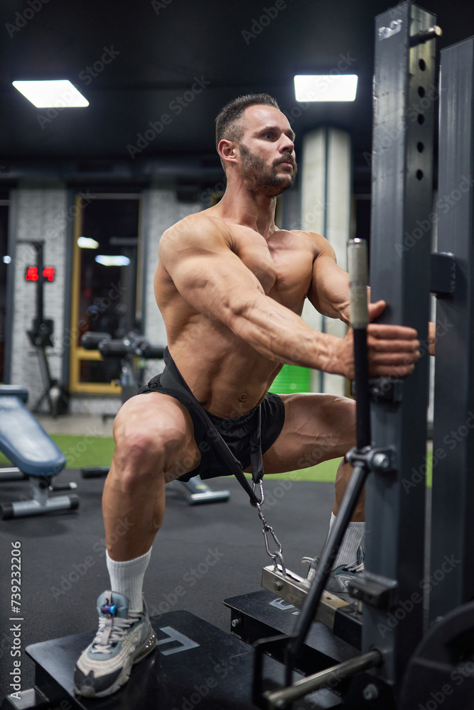 Concentrated muscular man in black shorts, doing squats with weight, training in modern gym. Low angle view of male Caucasian bodybuilder exercising at evening time. Concept of bodybuilding, crossfit. Concentrated muscular man in black shorts, doing squats with weight, training in modern gym. Low angle view of male Caucasian bodybuilder exercising at evening time. Concept of bodybuilding, crossfit.