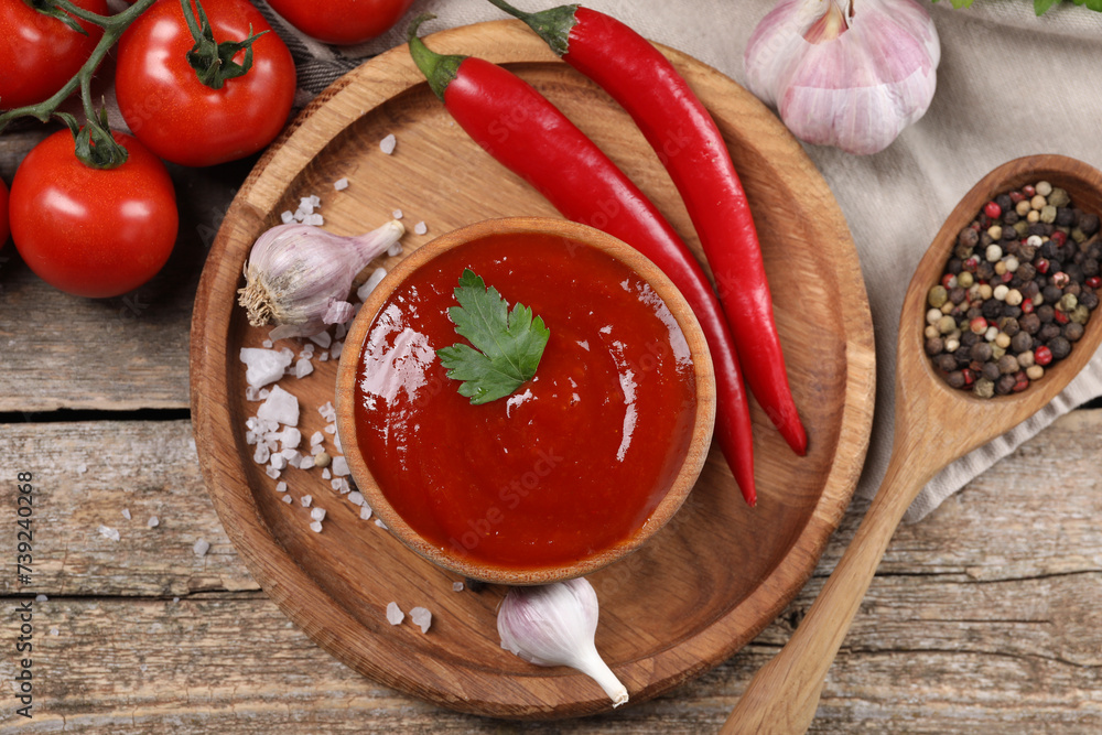 Delicious ketchup in bowl, products and spices on wooden table, flat lay. Tomato sauce Delicious ketchup in bowl, products and spices on wooden table, flat lay. Tomato sauce