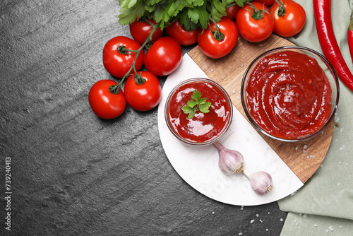 Organic ketchup in bowls and ingredients on black table, flat lay with space for text. Tomato sauce