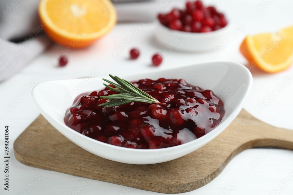 Fresh cranberry sauce and rosemary in bowl on white table, closeup Fresh cranberry sauce and rosemary in bowl on white table, closeup