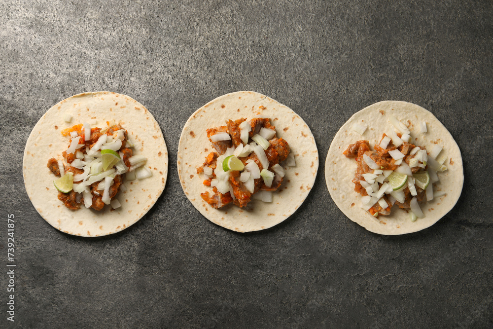 Delicious tacos with vegetables, meat and lime on grey textured table, flat lay Delicious tacos with vegetables, meat and lime on grey textured table, flat lay