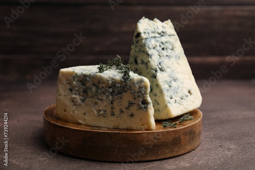 Photos Tasty blue cheese with thyme on brown table