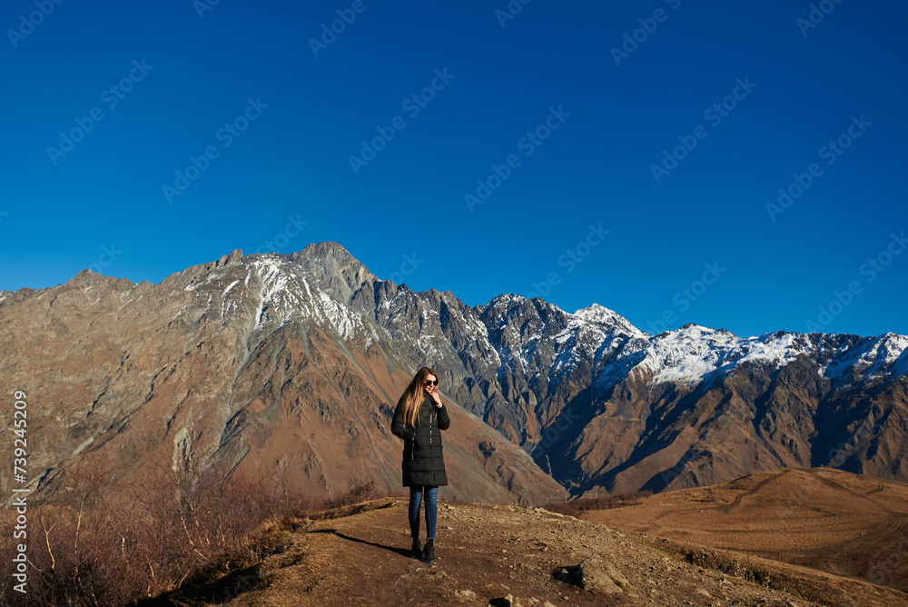 An attractive wanderer captivated by the splendor of the majestic brown mountains with snowy peaks.