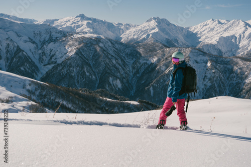 female snowboarder riding on slope of powdery snow in high mountains. Freeride at ski resort