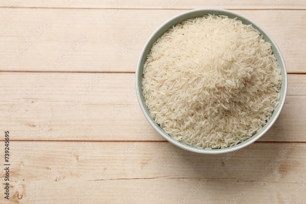 Raw basmati rice in bowl on white wooden table, top view. Space for text Raw basmati rice in bowl on white wooden table, top view. Space for text