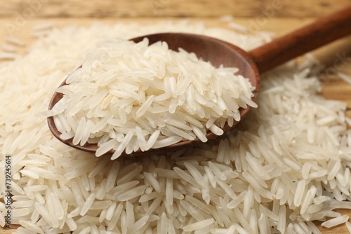 Raw basmati rice with wooden spoon on table, closeup