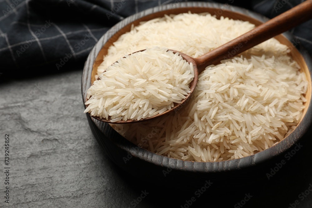Raw basmati rice in bowl and spoon on black table, closeup Raw basmati rice in bowl and spoon on black table, closeup