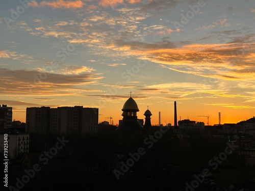 Panoramic view of the city during a fiery dramatic sunset with a very beautiful sky and black silhouettes of buildings.