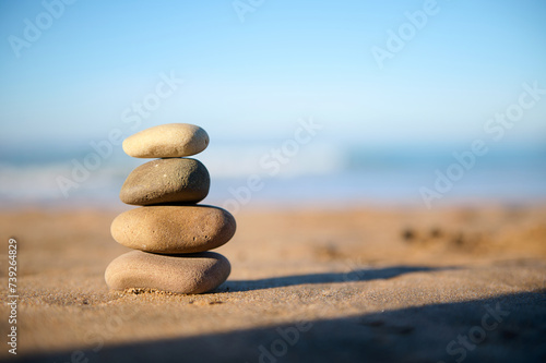 Still life with stacked pebbles  stones on the sandy beach against the background of Atlantic ocean with breaking waves