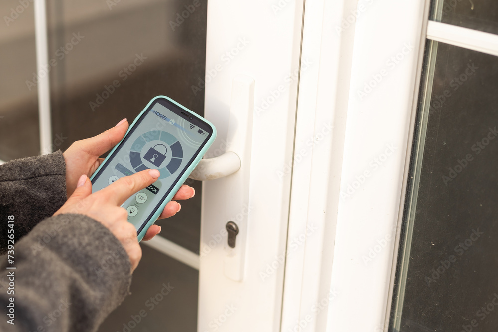 Smiling woman setting home security system with help of mobile application. Smiling woman setting home security system with help of mobile application.