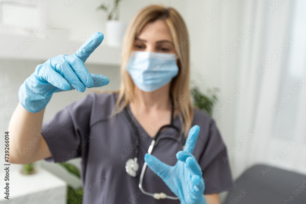 Tired female doctor. coronavirus. Young tired female doctor in protective mask and gloves shows finger. Tired female doctor. coronavirus. Young tired female doctor in protective mask and gloves shows finger.