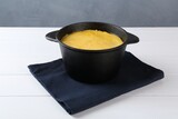 Fondue with tasty melted cheese and napkin on white wooden table