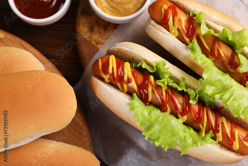 Canvas Print Tasty hot dogs and ingredients on wooden table, flat lay