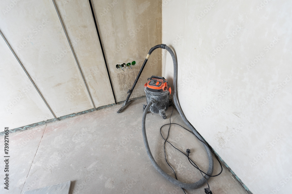 Industrial vacuum cleaner on the dusty floor of construction site.