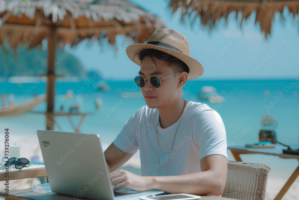 Asian Man Remotely Working from Beach on Laptop as Digital Nomad