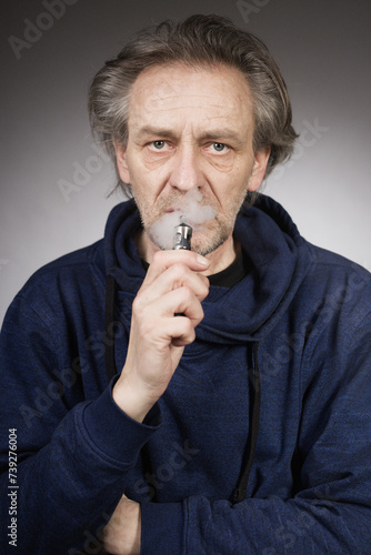 Older man with wrinkles on face skin smoking electronic cigarette