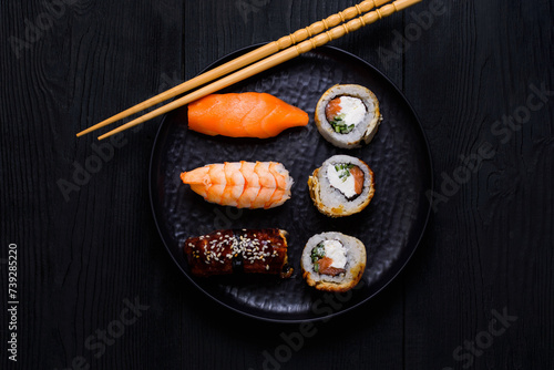 sushi and rolls on a black plate, on a black wooden background, top view