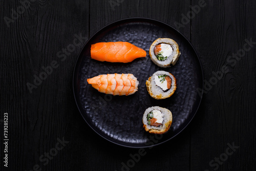 sushi and rolls on a black plate, on a black wooden background, top view