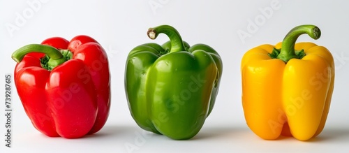 Vibrant trio of bell peppers in red, yellow, and green colors on white background
