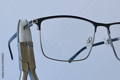Adjusting temples on metal eyeglass frame with holding pliers equipped with replaceable nylon jaws to reduce scratching and pressure damage of material. 