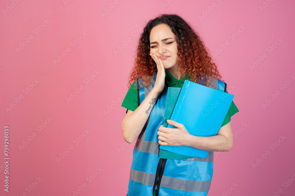 Front view of pretty woman standing with closed eyes, touching chhek, posing indoors, having toothache. Isolated on pink studio background. Front view of pretty woman standing with closed eyes, touching chhek, posing indoors, having toothache. Isolated on pink studio background.