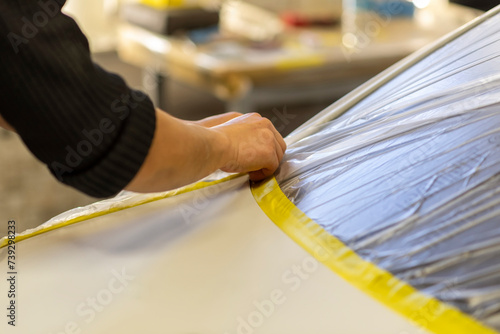 Applying masking tape to car bodywork.