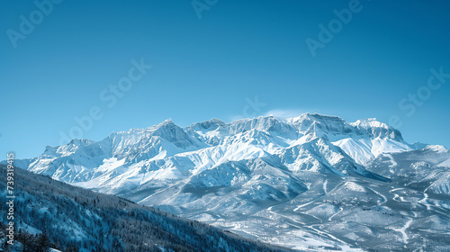 Clear blue skies reveal the stark beauty of rugged mountain peaks covered in pristine snow on a bright winter day.