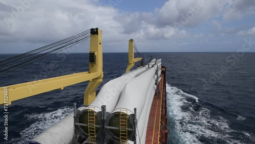 Blue dry cargo ship at sea. Multi purposes vessel carrying wind generators. View from bridge. 