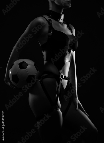 Beautiful girl body with black sexy underwear on a black background. She is holding a soccer ball in her hands. Sexy body, close up nudity.